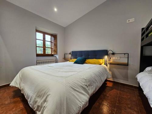 1 dormitorio con 1 cama blanca grande con almohadas amarillas en 10A04 Casa Petacos, en Pravia