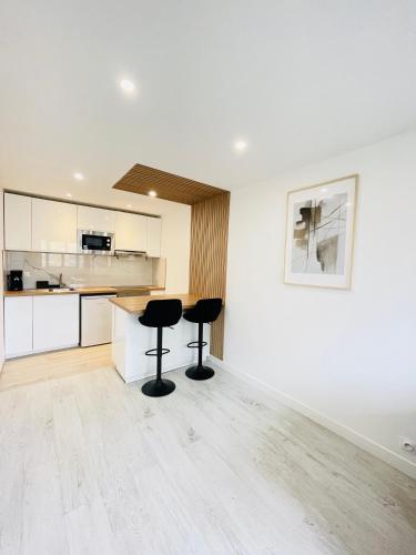 - une cuisine avec deux tabourets noirs dans une pièce dans l'établissement Charmant T2, à 15 min de Paris, à Argenteuil