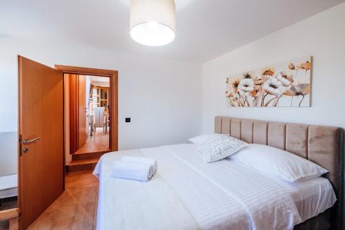 ein Schlafzimmer mit einem großen weißen Bett und einer Tür in der Unterkunft Roko Opaćac in Zadar