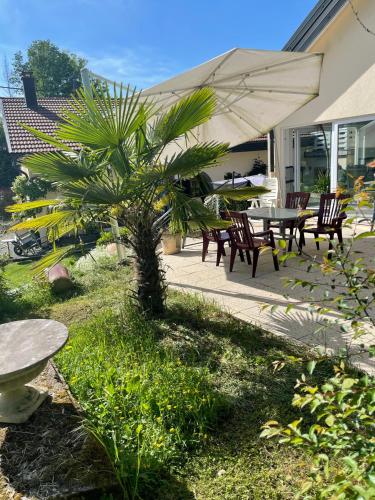 a patio with a table and chairs and an umbrella at Chambres d’hôtes plateau des mille étangs in Belonchamp