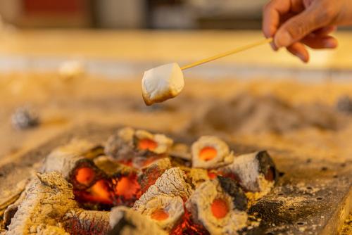 a person holding a piece of food on a stick at Atarayo Nishiizu Onsen in Izu