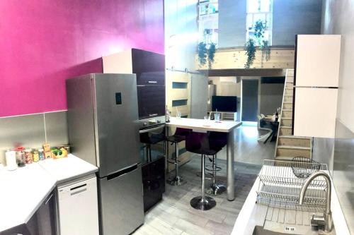 a kitchen with a refrigerator and a table in it at Duplex atypique 20’ de toulouse in Léguevin