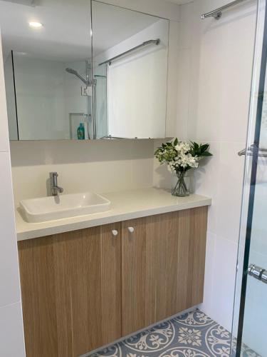 a bathroom with a sink and a vase of flowers at License To Chill • Couple’s Escape in Mooloolaba in Mooloolaba