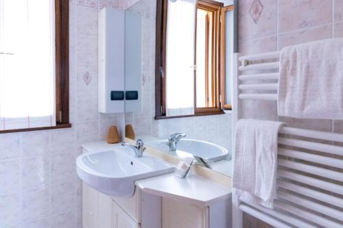 ein weißes Badezimmer mit einem Waschbecken und einem Spiegel in der Unterkunft {Il Blue di Grado} in Grado