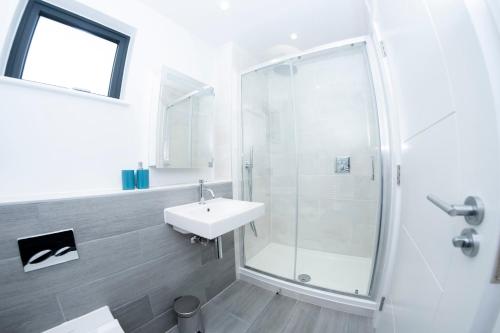 a white bathroom with a sink and a shower at 6 Putsborough - Luxury Apartment at Byron Woolacombe, only 4 minute walk to Woolacombe Beach! in Woolacombe