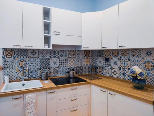 a kitchen with white cabinets and tiles on the wall at A casa di Chiara Salerno in Salerno
