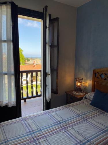 a bedroom with a bed and a view of a balcony at Hotel Rural El Texeu in Llanes