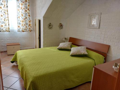 a bedroom with a green bed with two pillows on it at Casa con giardino Giacalone in Mazara del Vallo