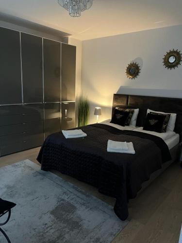 a bedroom with a large bed with black sheets and pillows at APARTAMENT VELVET in Świnoujście