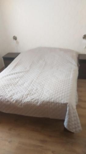 a white bed with a white comforter on it at Karpatia Vendeghaz 1201 Budapest in Budapest