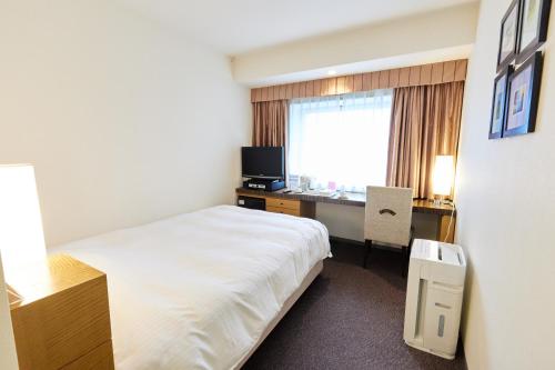 a hotel room with a bed and a desk and a window at Twin Leaves Hotel Izumo in Izumo