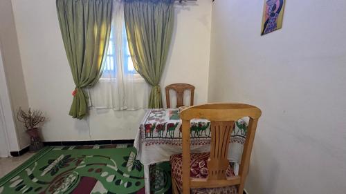 un tavolo e due sedie in una stanza con finestra di Pharaonicas a Al Aqālitah
