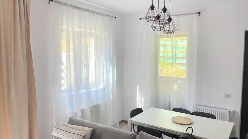 a white living room with a table and a window at Cosy&Minimalistic Apartments - Haret Building in Sinaia