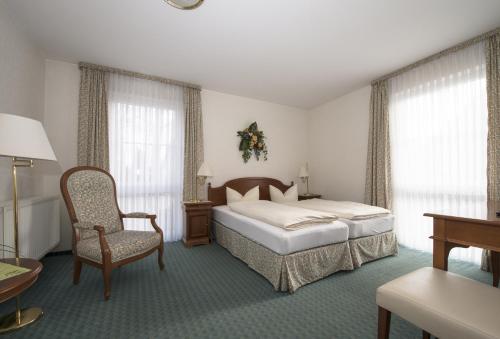 ein Hotelzimmer mit einem Bett und einem Stuhl in der Unterkunft Land-gut-Hotel Rohdenburg in Lilienthal