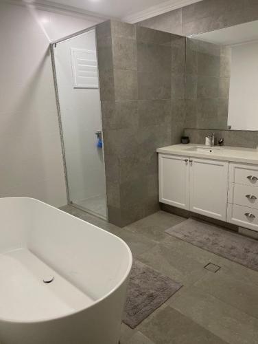 a bathroom with a tub and a shower and a sink at Room on Woodville in Perth