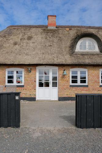 a brick house with a thatched roof and white doors at Strandfogedgården in Ulfborg