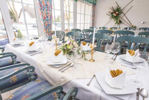 ein langer Tisch mit weißen Tischdecken und Blumen darauf in der Unterkunft Land-gut-Hotel Rohdenburg in Lilienthal