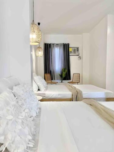 a white room with two beds and a window at NEW Modern Suite near Beach & Airport in Sudtungan
