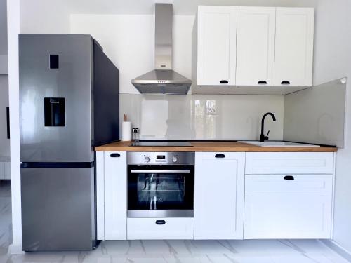 a kitchen with white cabinets and a stainless steel refrigerator at Apartments Cvitanović Korčula in Korčula
