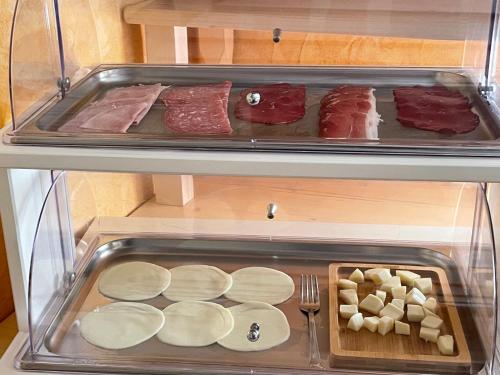 an open refrigerator with meat and other food items at Affittacamere S'Alzola in Porto Rotondo