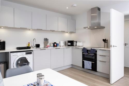 a kitchen with white cabinets and a dishwasher at 3 Putsborough - Luxury Apartment at Byron Woolacombe, only 4 minute walk to Woolacombe Beach! in Woolacombe