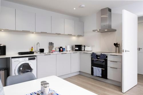 Una cocina con gabinetes blancos y lavavajillas. en 3 Putsborough - Luxury Apartment at Byron Woolacombe, only 4 minute walk to Woolacombe Beach!, en Woolacombe