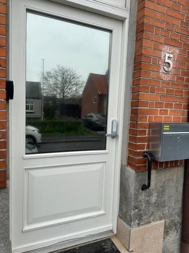 a white door with a window on a brick wall at Attic Room in Korsør