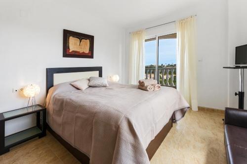 Un dormitorio con una cama grande y una ventana. en CB Living- Spacious sea view duplex with private jacuzzi, en Orihuela Costa