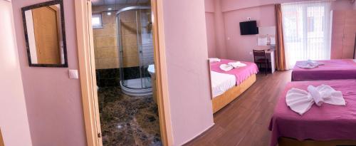 um quarto com 2 camas e uma casa de banho com um espelho em Figen Suite Hotel 2 em Çanakkale