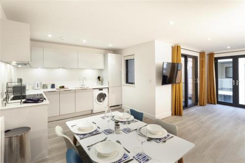 a kitchen and living room with a table and chairs at 5 Putsborough - Luxury Apartment at Byron Woolacombe, only 4 minute walk to Woolacombe Beach! in Woolacombe
