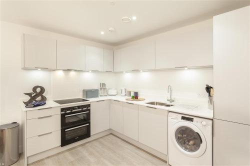 a kitchen with white cabinets and a washing machine at 5 Putsborough - Luxury Apartment at Byron Woolacombe, only 4 minute walk to Woolacombe Beach! in Woolacombe