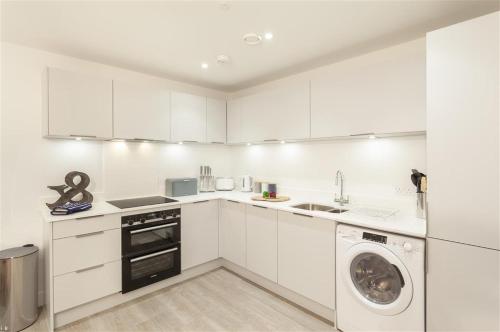 Una cocina con gabinetes blancos y lavadora. en 5 Putsborough - Luxury Apartment at Byron Woolacombe, only 4 minute walk to Woolacombe Beach!, en Woolacombe