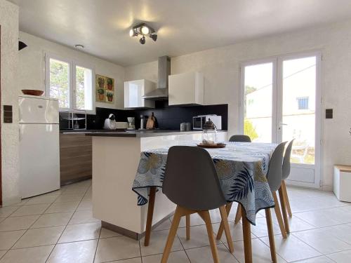 une cuisine avec une table avec des chaises et un réfrigérateur dans l'établissement Maison calme proche plage avec jardin – 8 couchages à Saint-Georges-d'Oléron - FR-1-246A-194, à Saint-Georges-dʼOléron