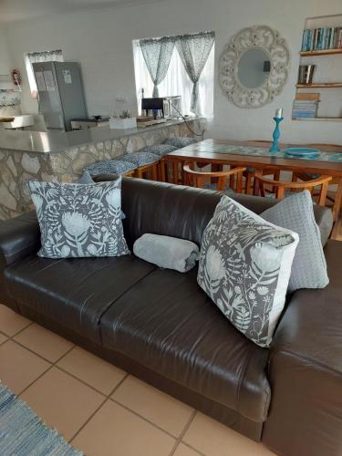 a brown leather couch with pillows in a living room at Lieflappie❤ in Stilbaai