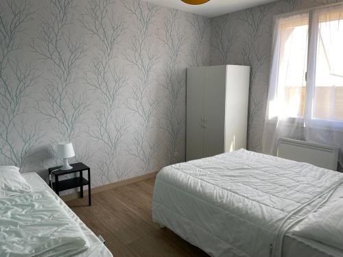 - une chambre avec un lit et un mur recouvert de papier peint dans l'établissement Le Chaton des Dunes, à Denneville-Plage