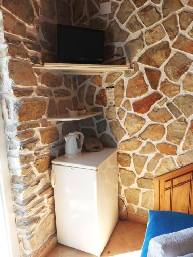 a room with a stone wall with a tv on a refrigerator at Aigaio View Studios & Rooms in Azolimnos