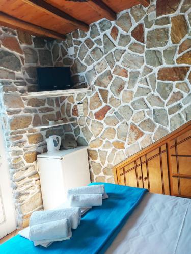 a room with a stone wall and a bed with towels at Aigaio View Studios & Rooms in Azolimnos