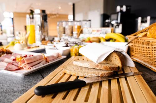 een tafel met een snijplank met brood en een mes bij Coreum Hotel in Stockstadt am Rhein
