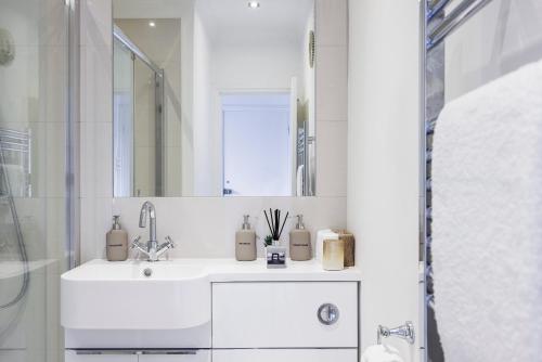 a white bathroom with a sink and a shower at Stylish Apartment Opposite Westfields in London