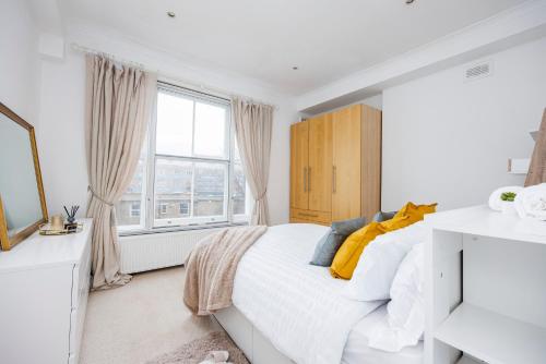 a bedroom with a white bed and a window at Stylish Apartment Opposite Westfields in London