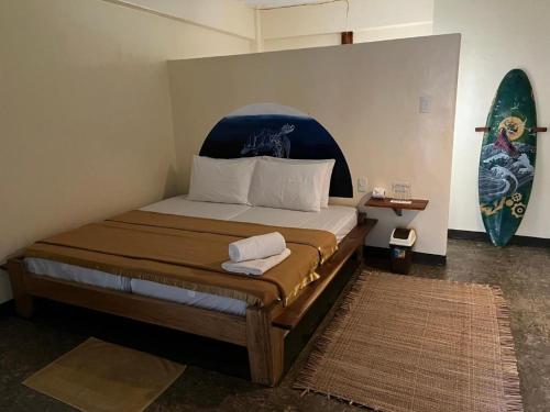 1 dormitorio con 1 cama con tabla de surf en la pared en Lexias Hostel and Workspace - Siargao en Catagnan