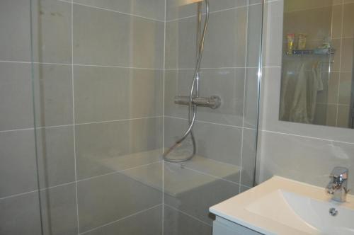 une salle de bain avec une douche avec un lavabo et un miroir dans l'établissement Espace 43, Sète Corniche Plage, à Sète