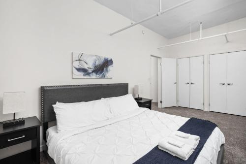 a bedroom with a large white bed with a blue blanket at 2BR 2BA In The Block Apartment by CozySuites in Indianapolis