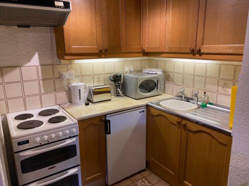a kitchen with a stove and a sink and a microwave at Bellfield Country Suites in Masham