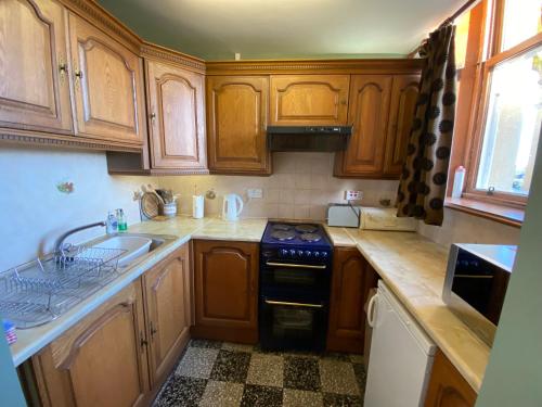 a kitchen with wooden cabinets and a stove and a sink at Bellfield Country Suites in Masham
