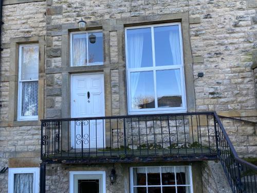 a stone building with a balcony and a white door at Bellfield Country Suites in Masham