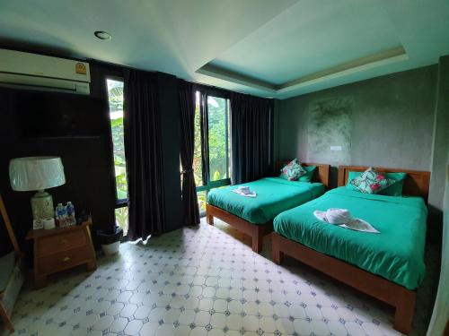 sypialnia z 2 łóżkami pojedynczymi i zieloną pościelą w obiekcie Baan Wualamphong บ้านวัวลำพอง w mieście Bangkok