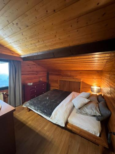 un lit dans une chambre avec un mur en bois dans l'établissement Chalet les Marmottes, à Saint-Jean-de-Sixt
