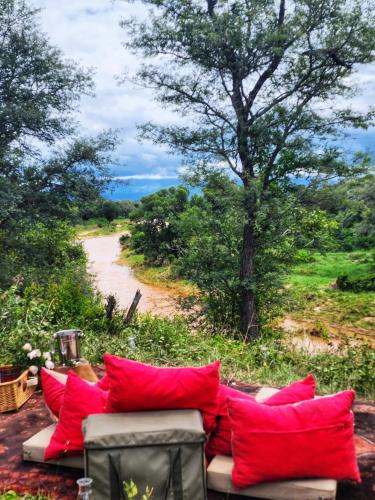 a couch with red pillows sitting in front of a dirt road at Karongwe - Becks Safari Lodge in Hoedspruit
