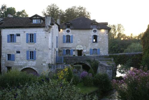 an old stone house with a bridge and flowers at Hostellerie Les Griffons in Brantome en Perigord